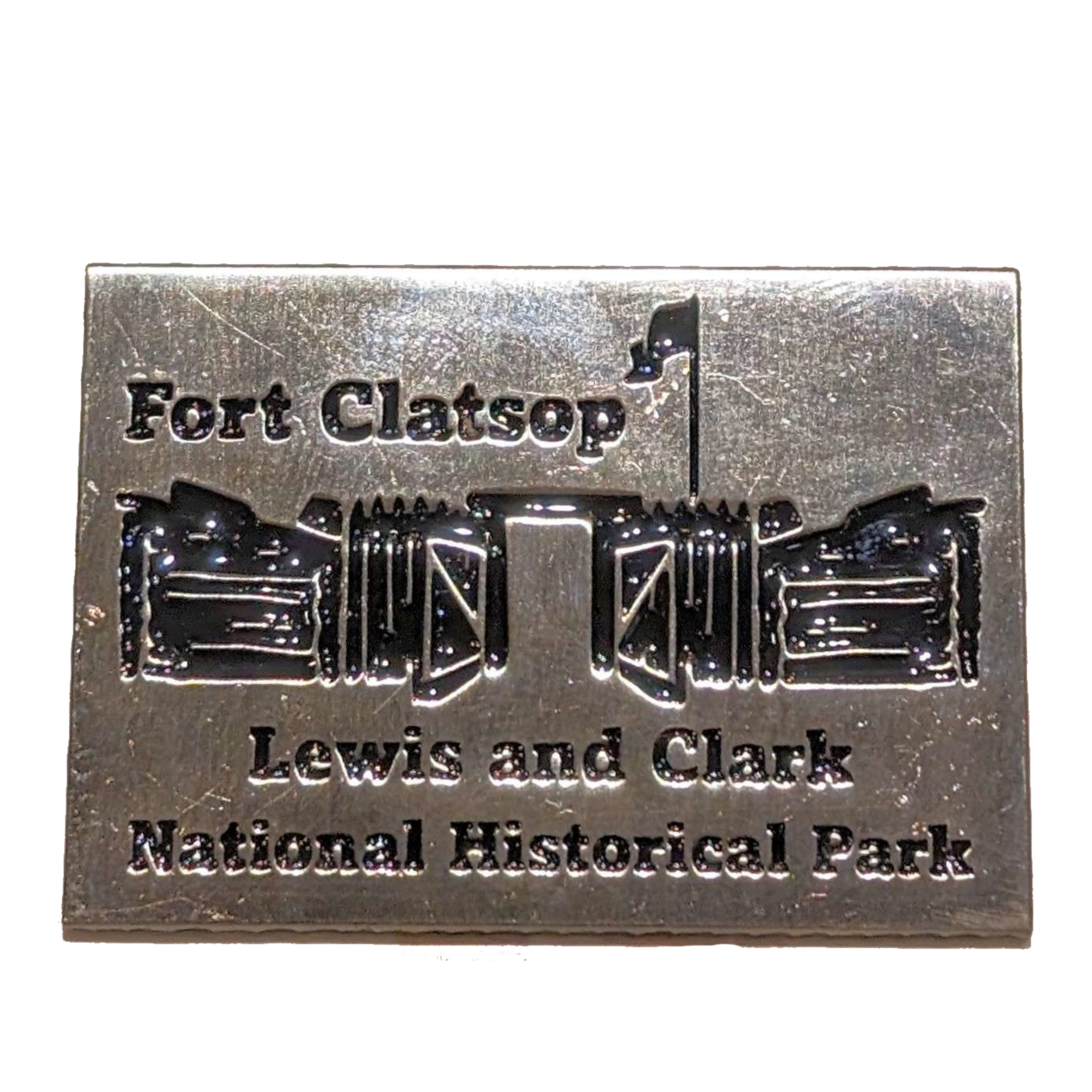 A rectangular metal pin with the text "Fort Clatsop Lewis and Clark National Historical Park" and an a depiction of Fort Clatsop.